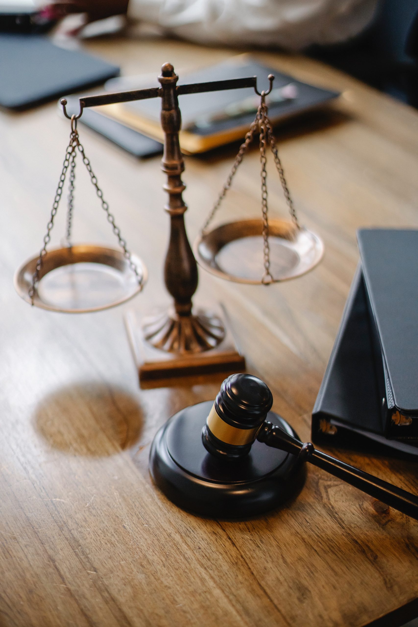 A gavel and scales sit on a wooden desk