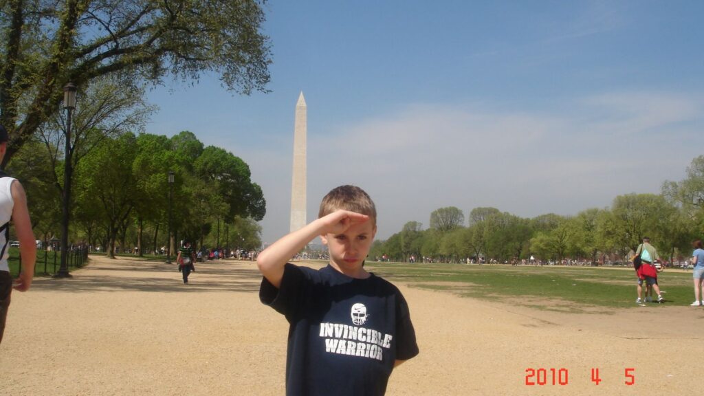 Eight-year-old Noah Samuel-Siegel saluting in front of the Washington Monument